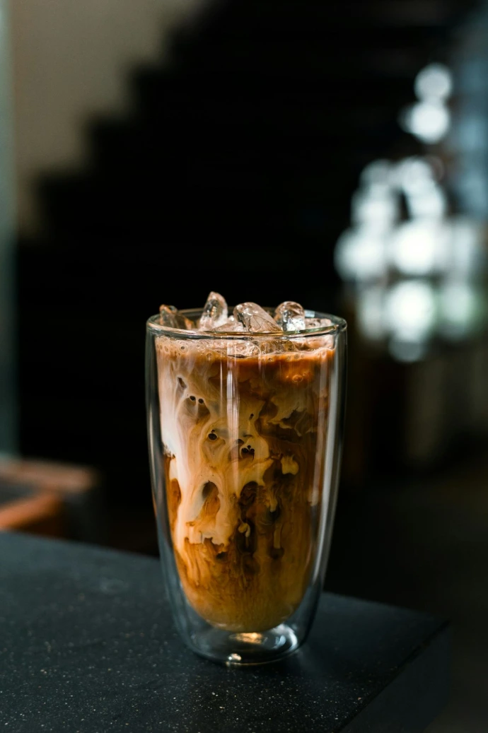 a glass filled with liquid and ice on top of a table